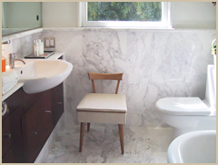 A small bathroom was opened up, clad in marble, and provided with much-needed storage.