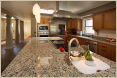 The island includes a sink for prep work and a large, professional cook top and vent.